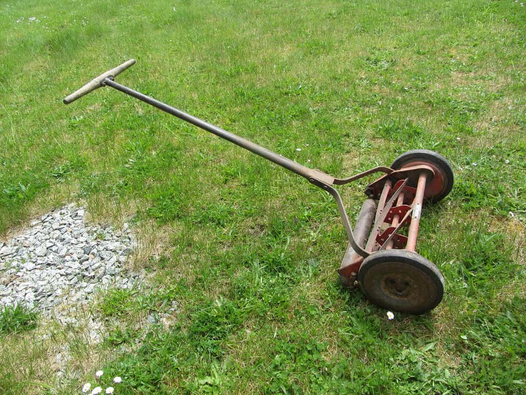 Push lawn mower standing on a grass lawn